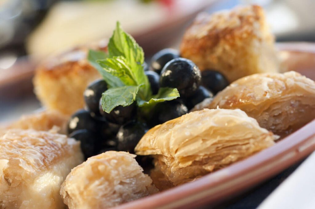 A delicious Greek-Cypriot dessert, featuring a sweet pastry like baklava or loukoumades, drizzled with honey and sprinkled with crushed nuts, offering a rich and indulgent treat.